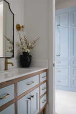 Custom vanity featuring wood-finish framing and light blue cabinet fronts with brass hardware