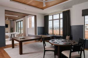 Recreation room featuring wood-finish flooring, wainscoting, and large windows with outdoor scenery