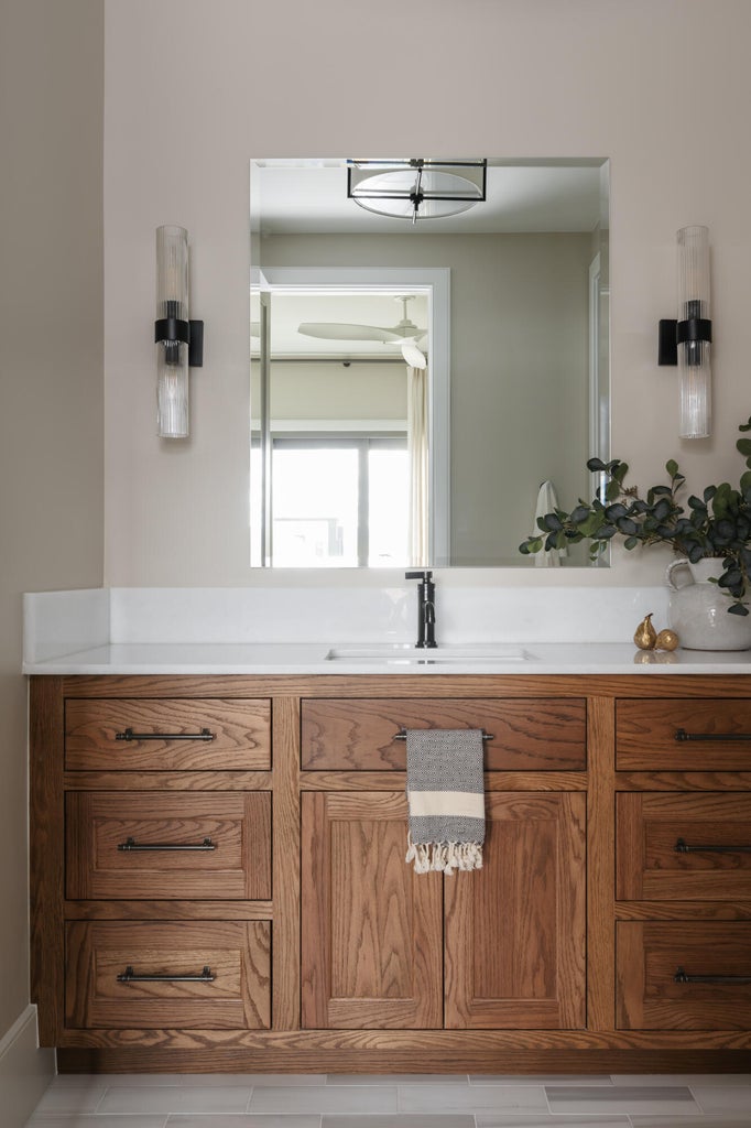 Wood-finish vanity with ample storage, a white countertop, and an undermount sink