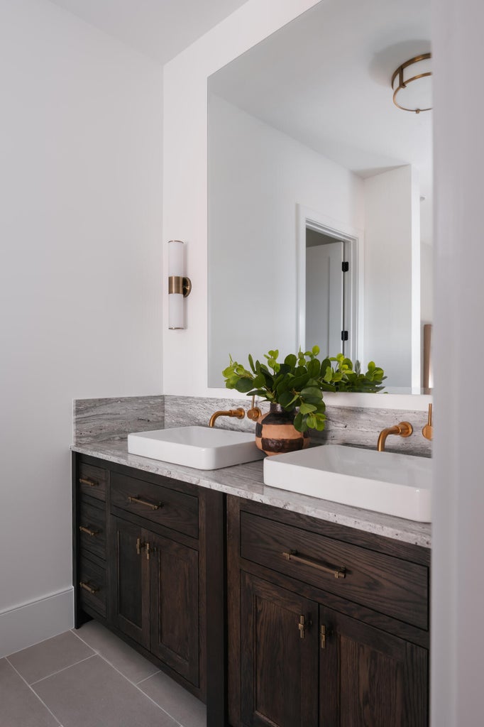 Double vanity with dark wood-finish cabinetry, white rectangular vessel sinks, and wall-mounted brass faucets