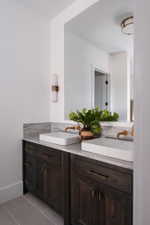 Double vanity with dark wood-finish cabinetry, white rectangular vessel sinks, and wall-mounted brass faucets