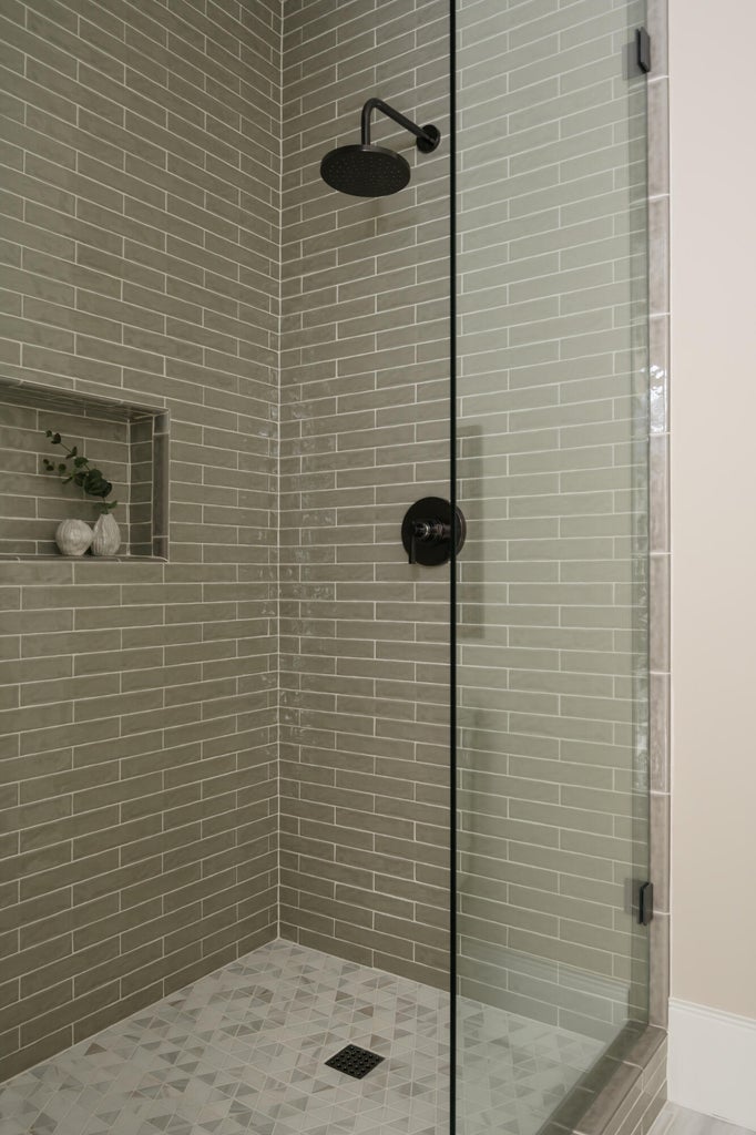 Glass-enclosed shower featuring a matte black rainfall showerhead and coordinating fixtures