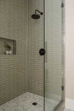 Glass-enclosed shower featuring a matte black rainfall showerhead and coordinating fixtures