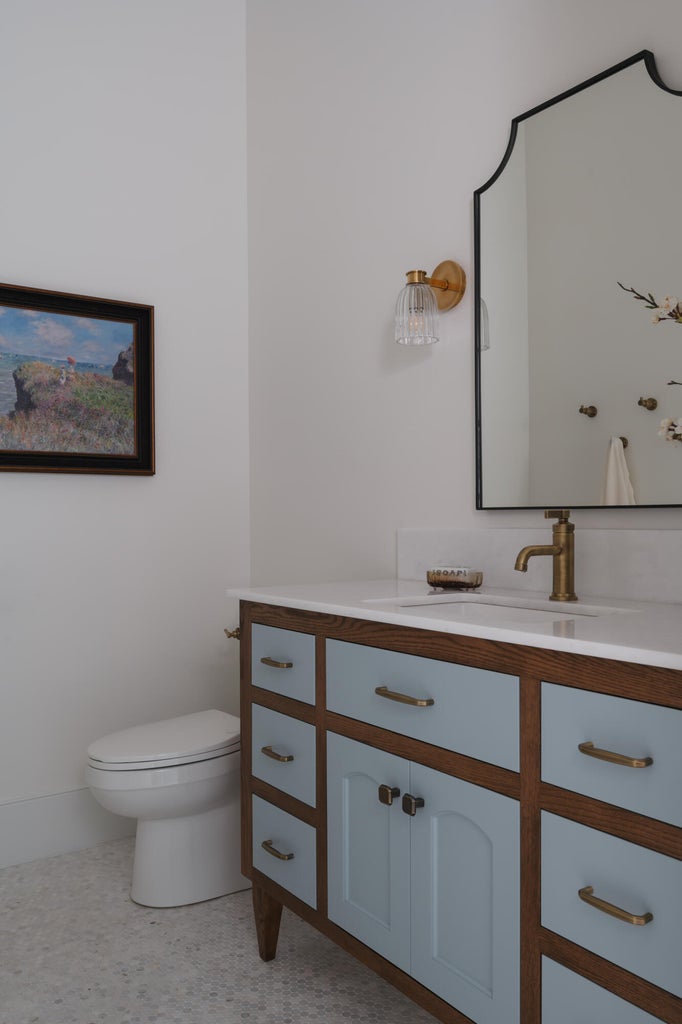 Bathroom vanity featuring blue-painted cabinetry and wood-finish framing