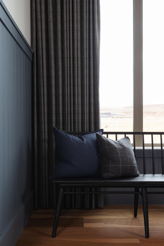 Vertical paneling with a rich blue finish, complemented by full-length dark drapery and wood-finish flooring