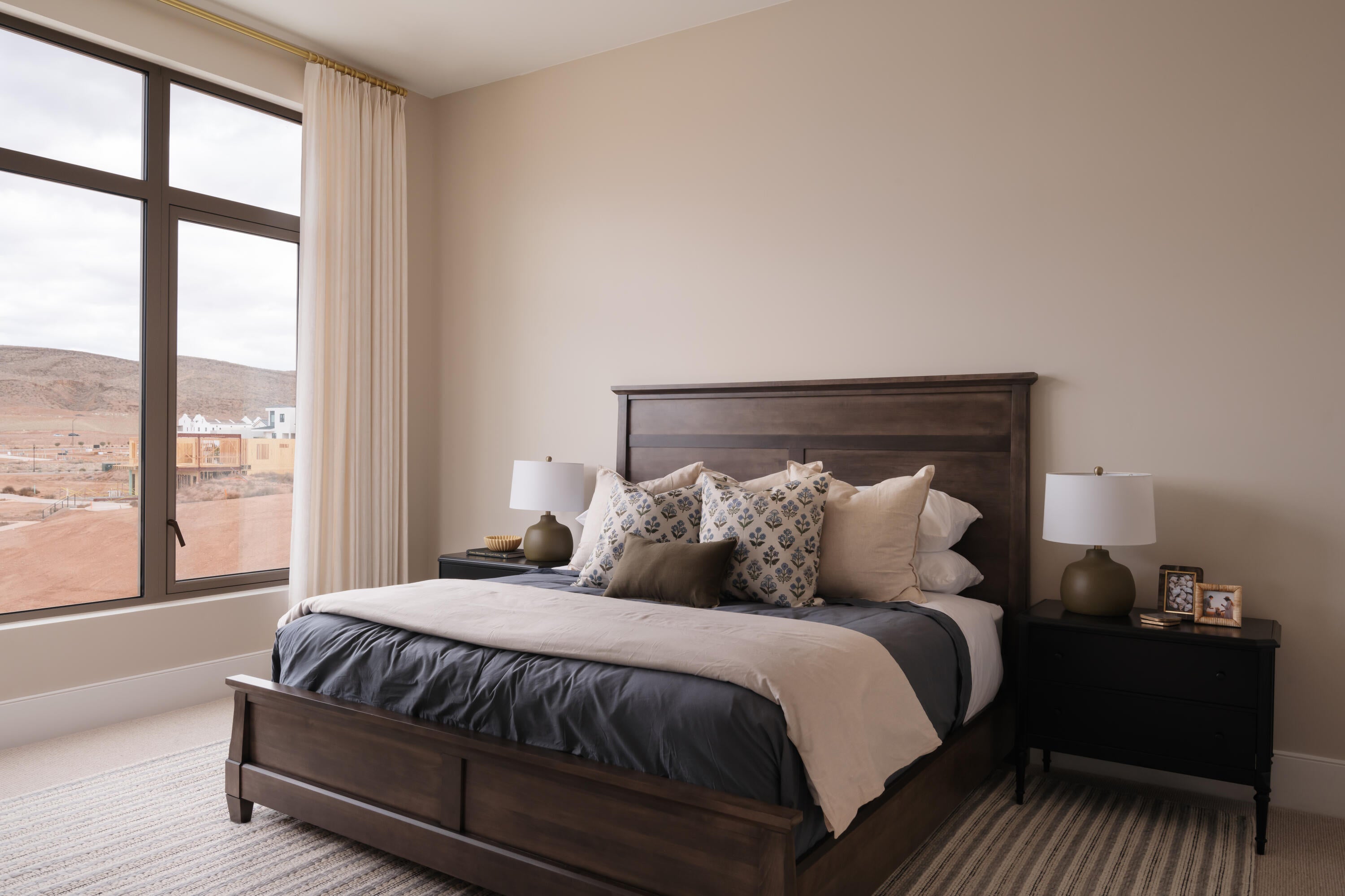 Room featuring a large window with dark frames, light-toned walls, and a light-colored area rug