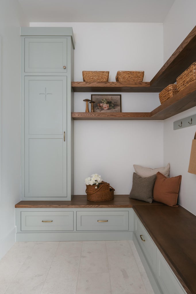 Built-in cabinetry with light blue-gray finish, wood-finish countertops, open wood-finish shelving, integrated storage drawers, and light-colored tile flooring