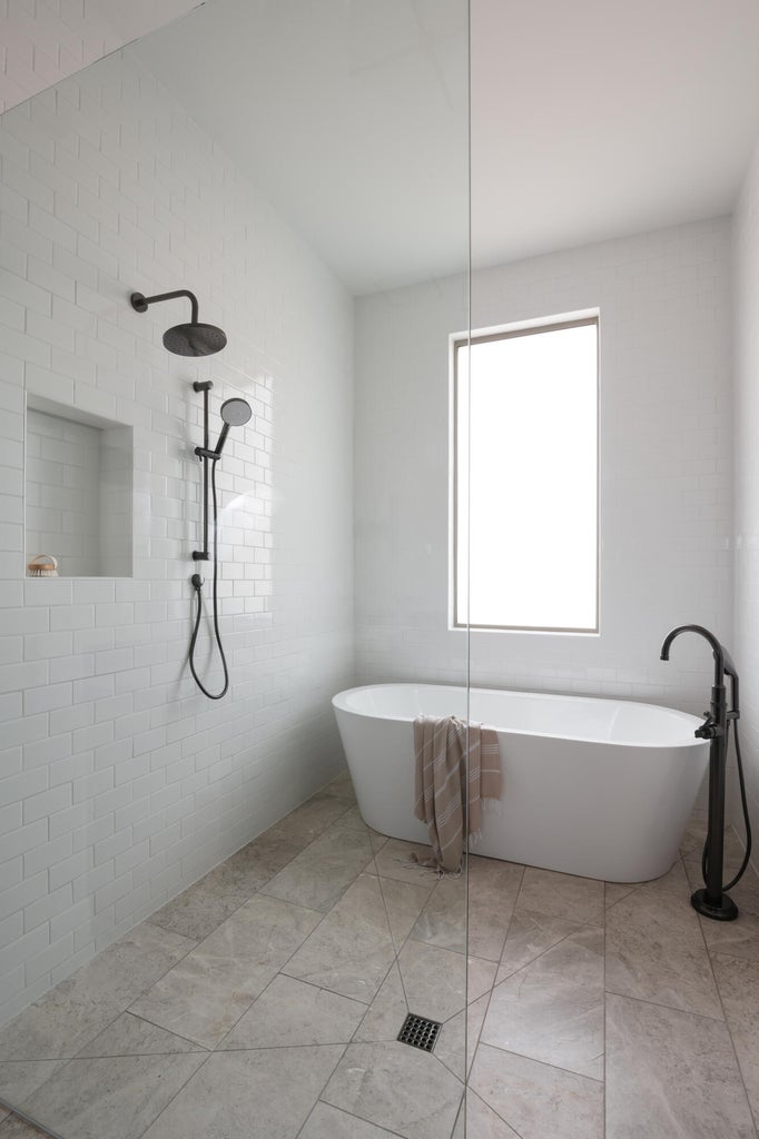 Spacious bathroom featuring a freestanding soaking tub with a floor-mounted matte black faucet