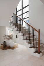 Grand staircase featuring wood-finish handrails, black metal balusters, and carpeted treads