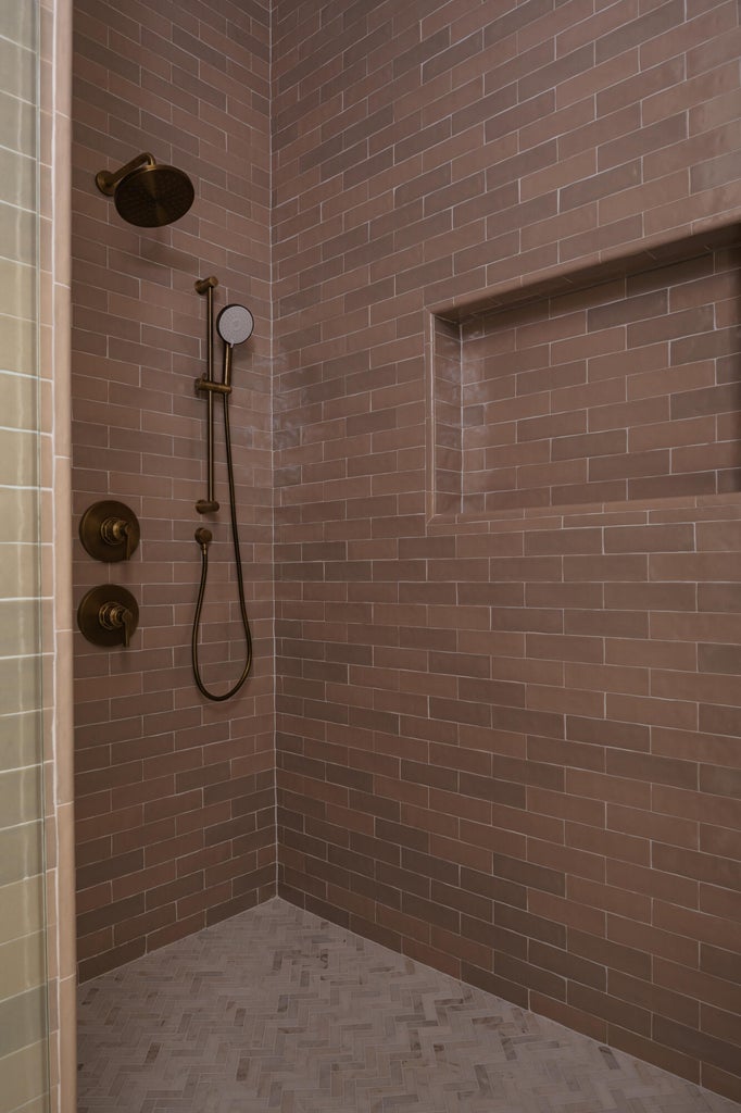 Shower stall with bronze-finish fixtures, a built-in niche, and brown subway tile walls