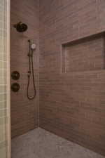 Shower stall with bronze-finish fixtures, a built-in niche, and brown subway tile walls