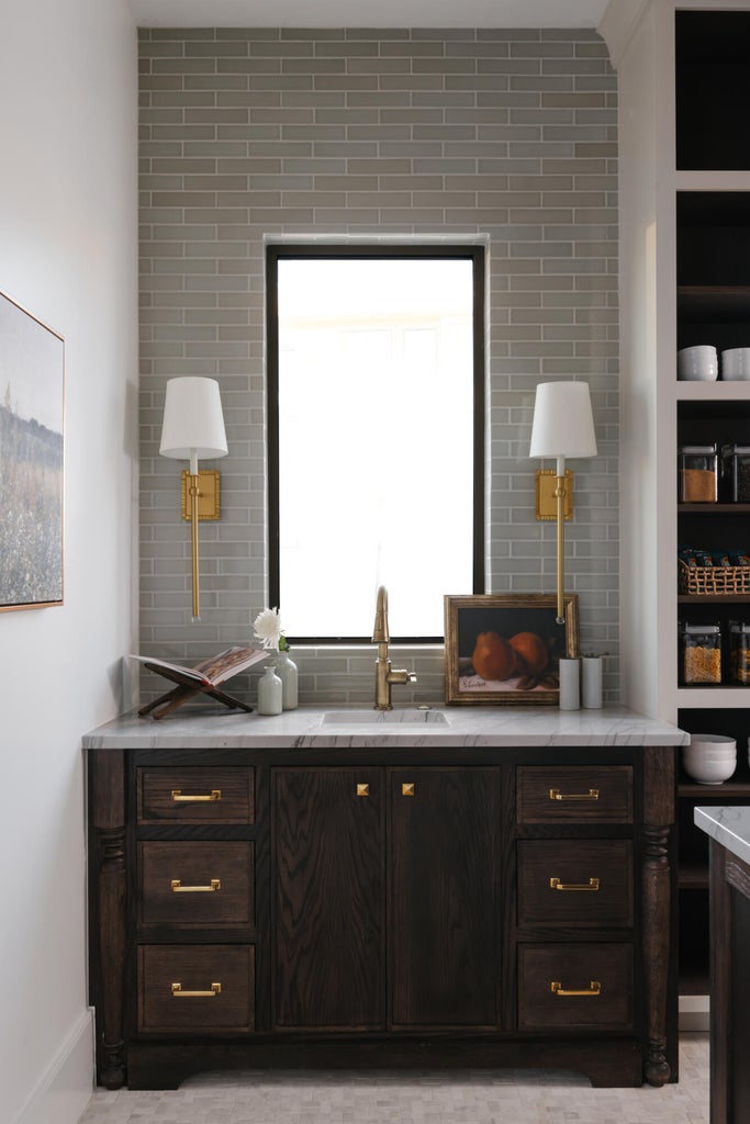 Dark wood vanity featuring brass hardware, a white countertop, and an undermount sink with a brass faucet
