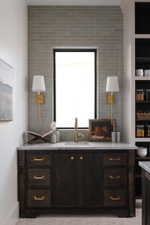 Dark wood vanity featuring brass hardware, a white countertop, and an undermount sink with a brass faucet