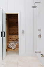 Integrated sauna with cedar interior and multi-tiered seating, featuring a clear glass door with matte black hardware