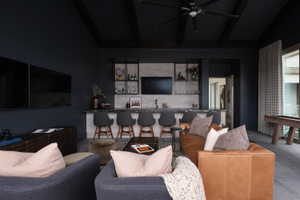 Entertainment room featuring a wet bar with stone countertops and open shelving, a coffered ceiling with a ceiling fan, and large format tile flooring