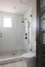 Frameless glass shower enclosure featuring white subway tile walls and a basketweave tile floor