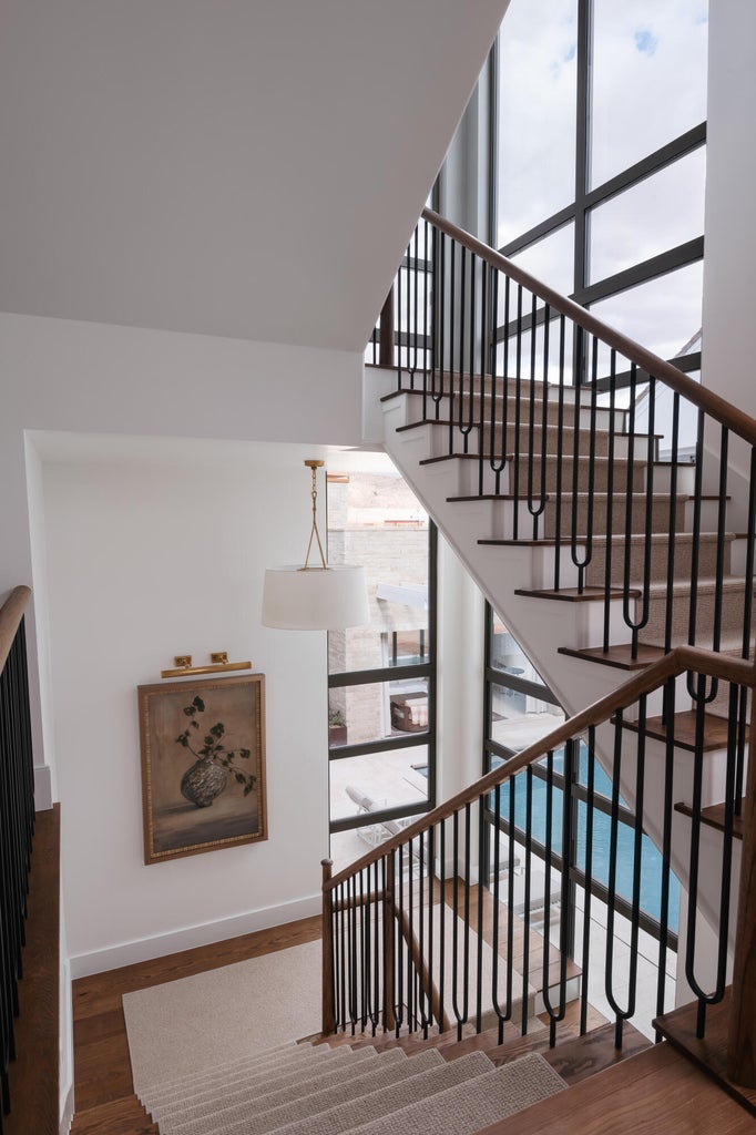 Staircase featuring wood-finish treads, a light-toned carpet runner, and dark metal balusters with a wood-finish handrail