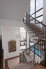 Staircase featuring wood-finish treads, a light-toned carpet runner, and dark metal balusters with a wood-finish handrail