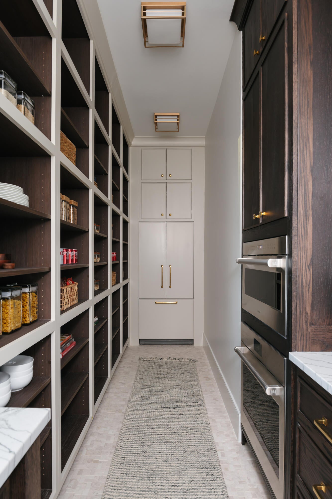Expansive pantry featuring extensive built-in shelving, integrated refrigerator and freezer, built-in stainless steel double ovens, and recessed ceiling lighting