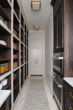 Expansive pantry featuring extensive built-in shelving, integrated refrigerator and freezer, built-in stainless steel double ovens, and recessed ceiling lighting