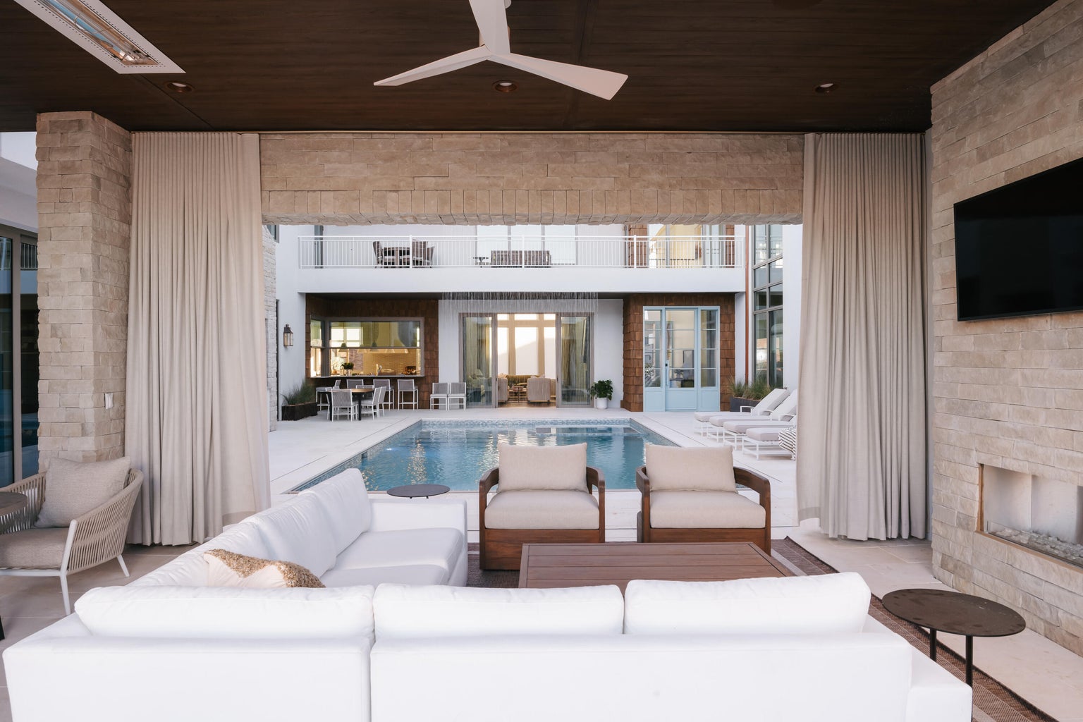 Expansive covered patio featuring a built-in fireplace, ceiling fan, and recessed lighting