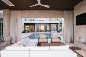 Expansive covered patio featuring a built-in fireplace, ceiling fan, and recessed lighting