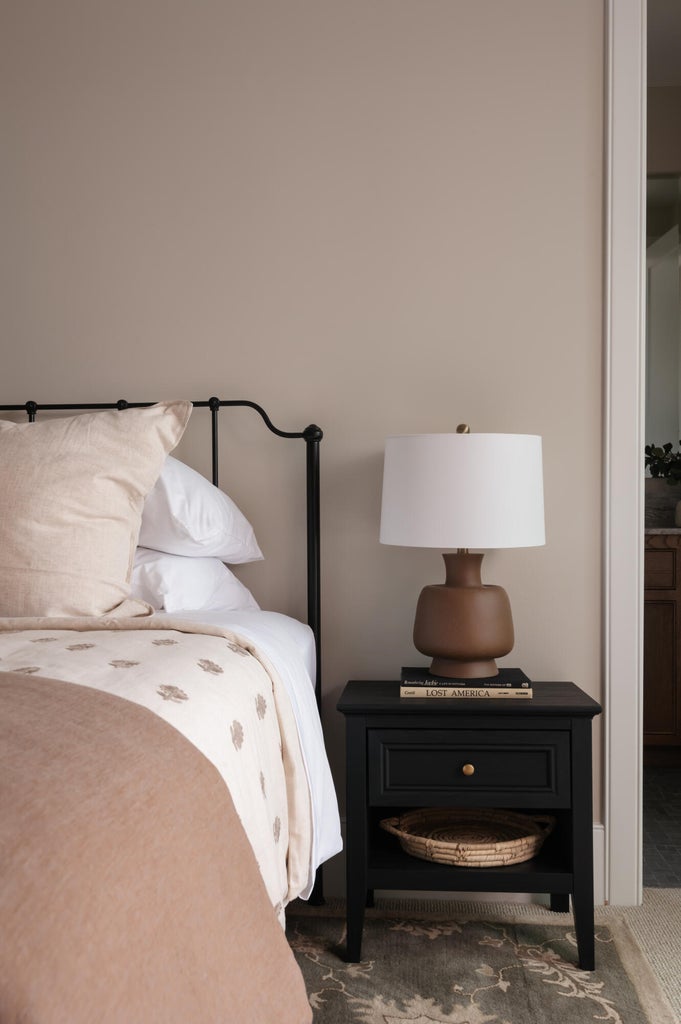 Neutral wall tones complement the dark wood-finish nightstand featuring a single drawer and open shelf