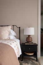 Neutral wall tones complement the dark wood-finish nightstand featuring a single drawer and open shelf