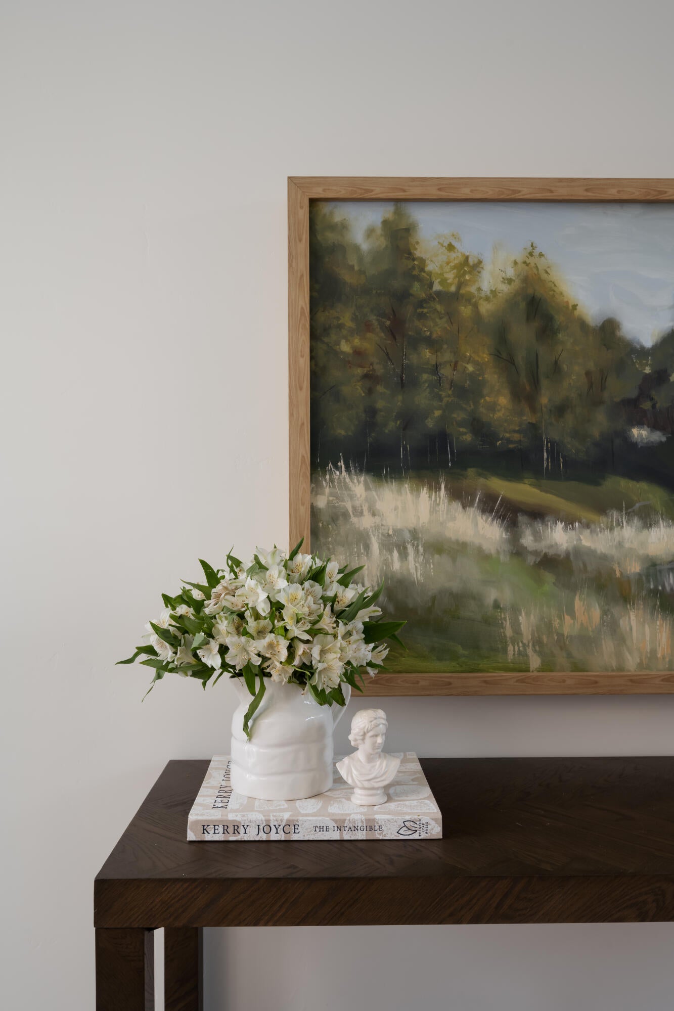 Wall-mounted artwork with a light wood frame above a dark wood-finish console table