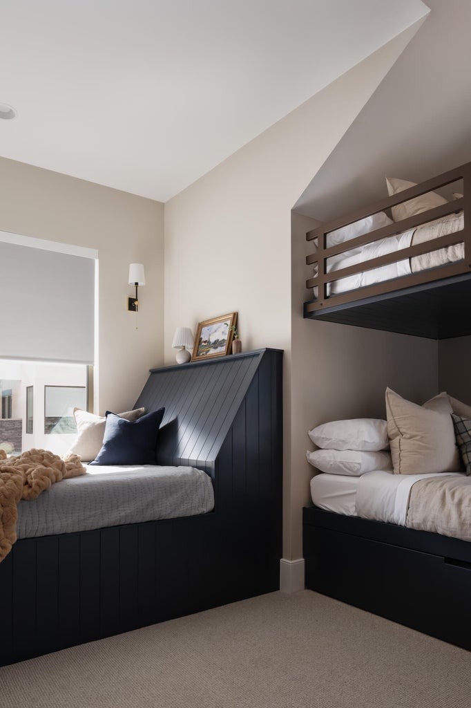 Built-in bed frames with integrated storage, neutral-toned carpeting, recessed ceiling lighting, and wall-mounted sconces