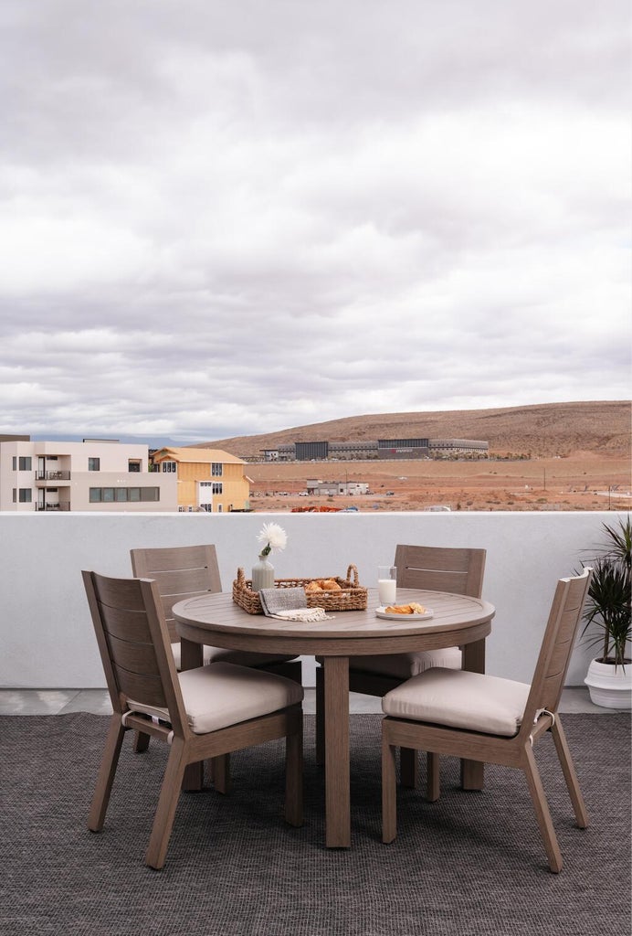 Rooftop patio featuring a low perimeter wall, dark woven outdoor rug, and distant desert landscape