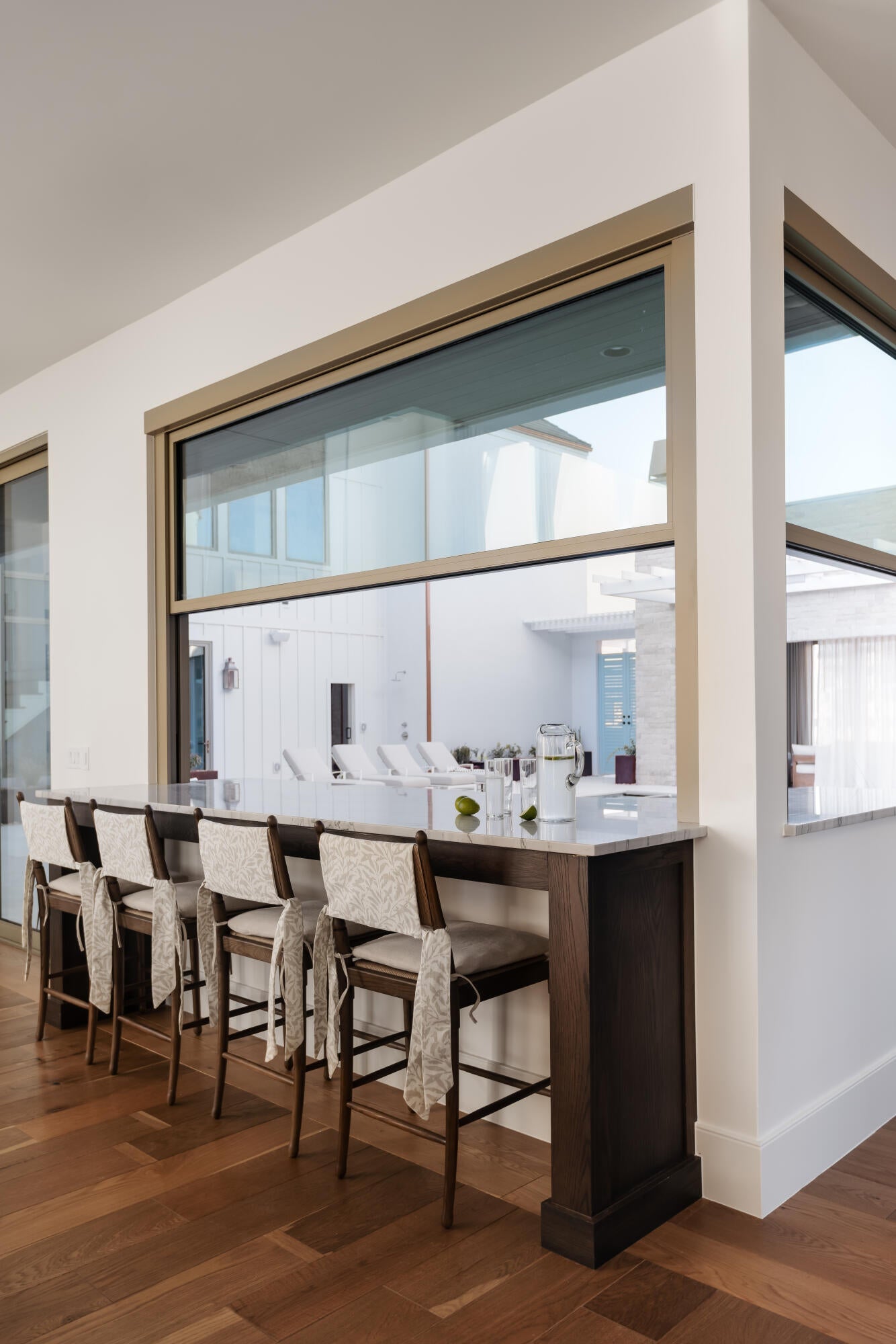 Counter-height bar seating with a light-toned countertop, wood-finish flooring, and expansive windows