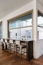 Counter-height bar seating with a light-toned countertop, wood-finish flooring, and expansive windows