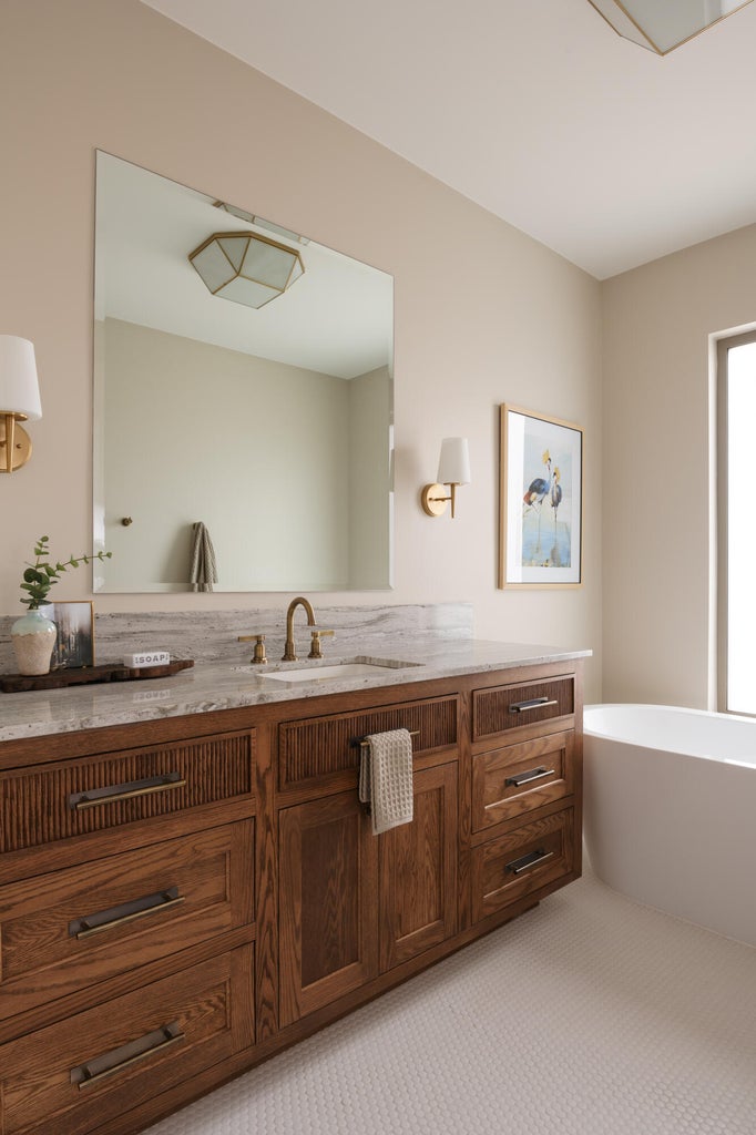 Wood-finish vanity featuring multiple storage drawers and cabinets, topped with a stone-finish countertop and an undermount sink