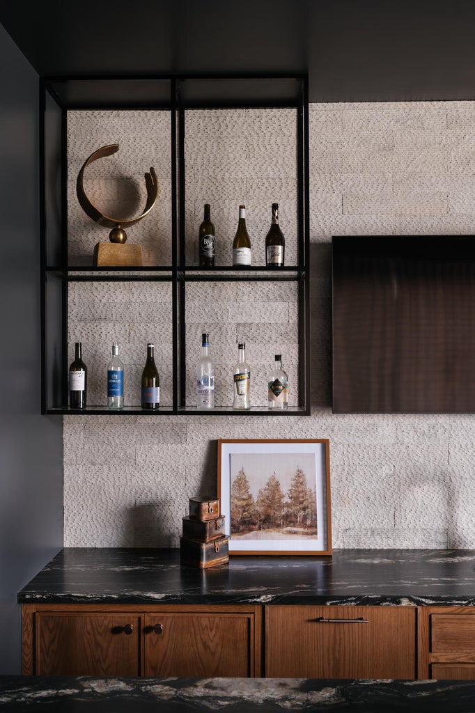 Built-in dry bar featuring black granite countertops, wood cabinetry, a textured backsplash, and open metal shelving