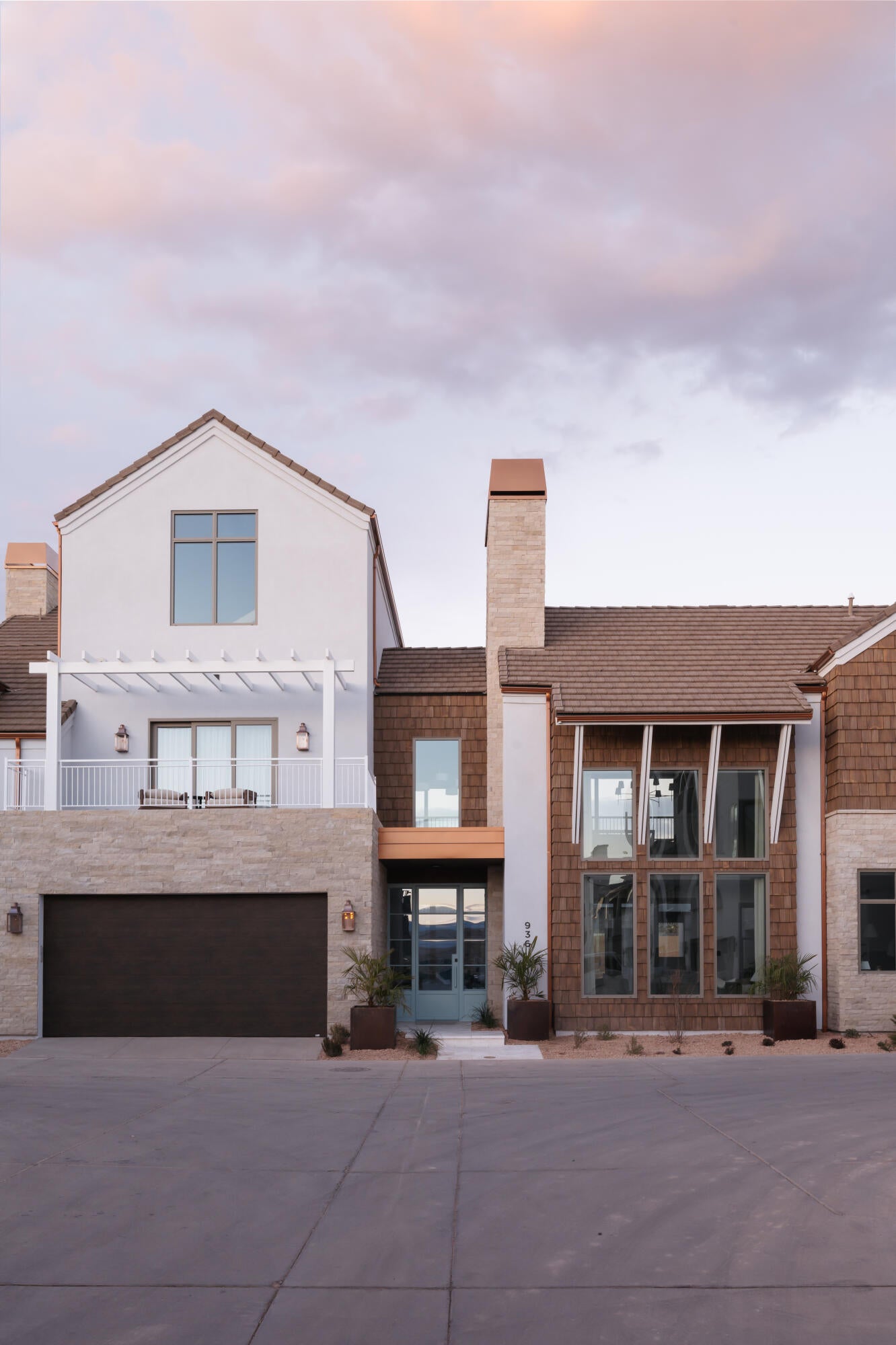 Contemporary facade featuring mixed materials including white stucco, natural wood shingle siding, and stacked stone accents