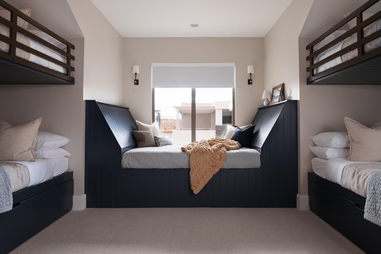 Built-in window seat with a paneled base, flanked by two wall-mounted bunk beds featuring dark wood frames and integrated storage drawers