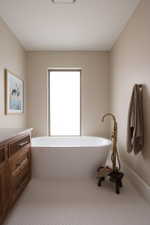Freestanding soaking tub with floor-mounted brass faucet, set against a window