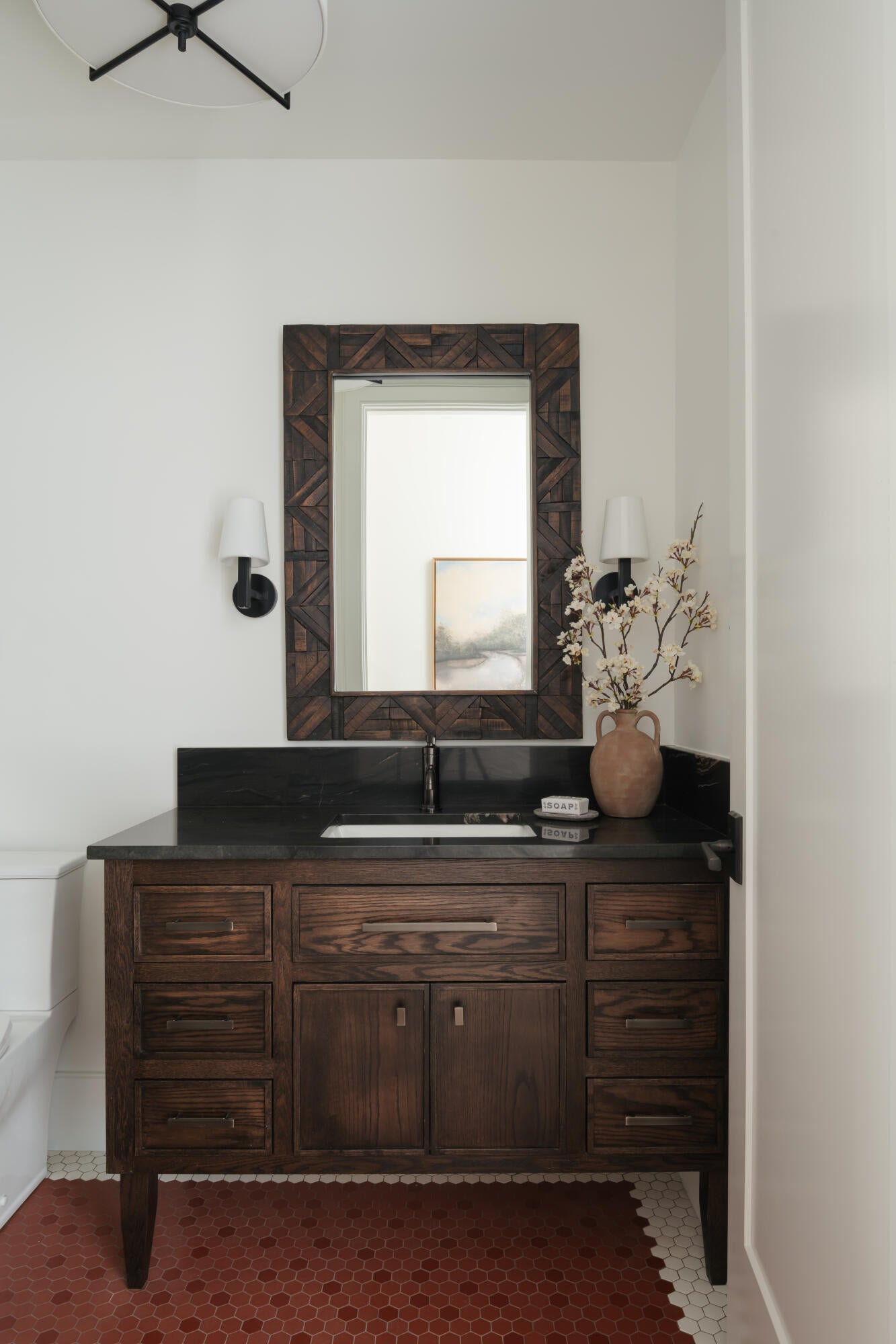 Dark wood vanity with multiple storage drawers and a cabinet, featuring a dark countertop and integrated sink