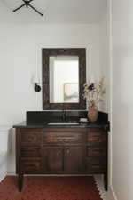 Dark wood vanity with multiple storage drawers and a cabinet, featuring a dark countertop and integrated sink