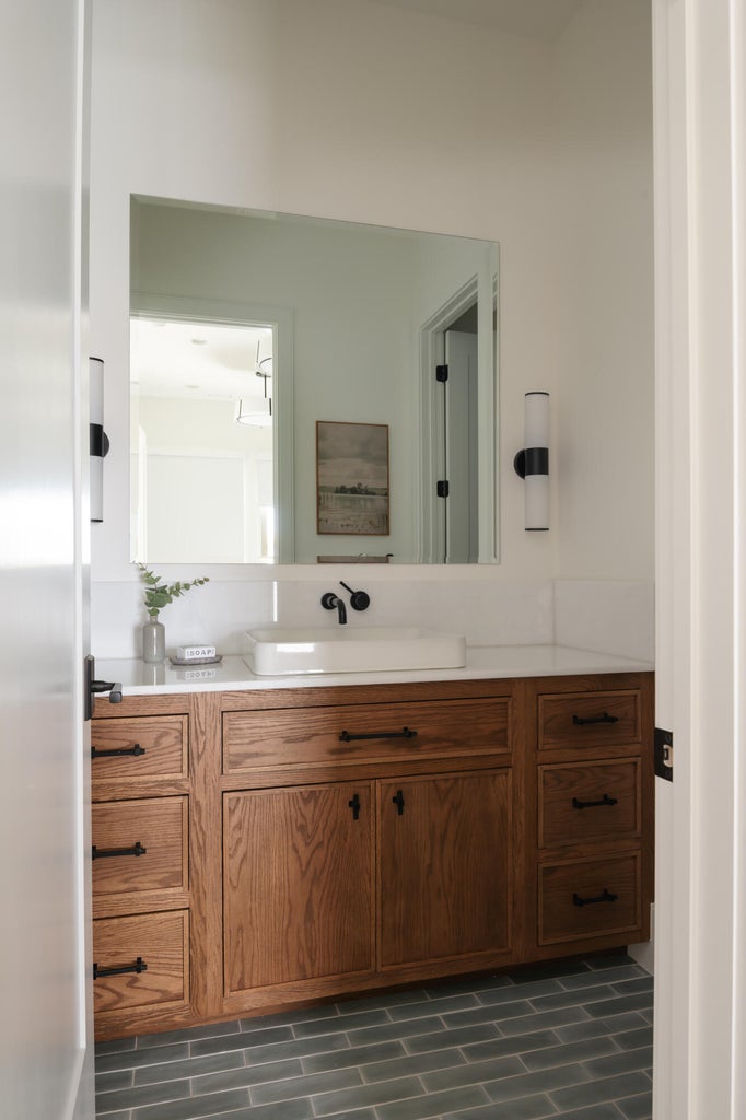 Custom wood cabinetry with matte black hardware, a white vessel sink, and a wall-mounted faucet