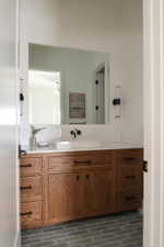 Custom wood cabinetry with matte black hardware, a white vessel sink, and a wall-mounted faucet