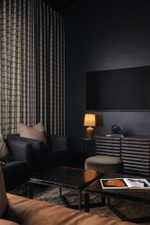 Dark-toned room featuring a large mounted display, full-height drapery, and dark walls