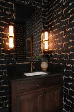Vanity with dark wood cabinetry, integrated sink, and a dark countertop