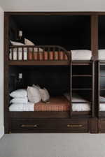 Built-in bunk beds with dark wood-finish framing, integrated ladders, and brass pull hardware on lower storage drawers