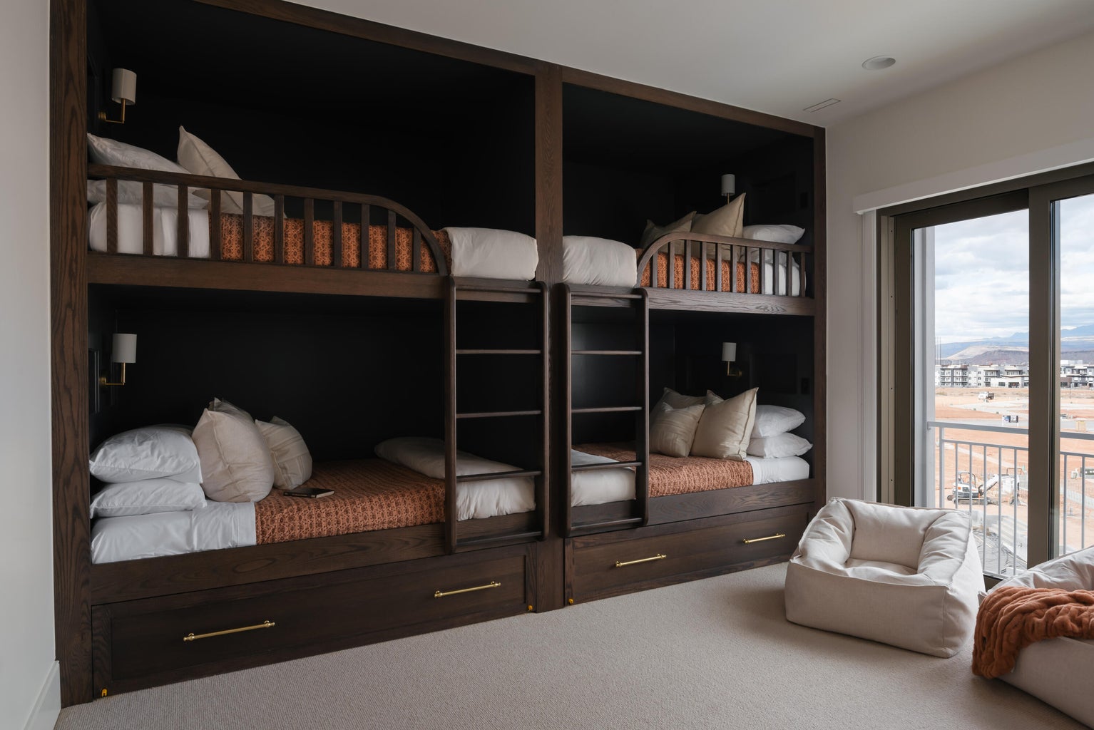 Built-in wood-finish bunk beds with integrated ladders and wall-mounted sconces