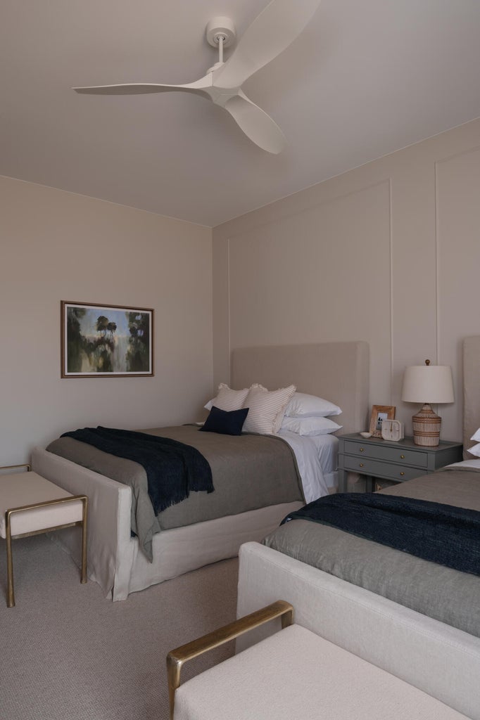 Neutral-toned room featuring a contemporary ceiling fan, wall paneling, and carpeted flooring