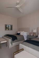 Neutral-toned room featuring a contemporary ceiling fan, wall paneling, and carpeted flooring