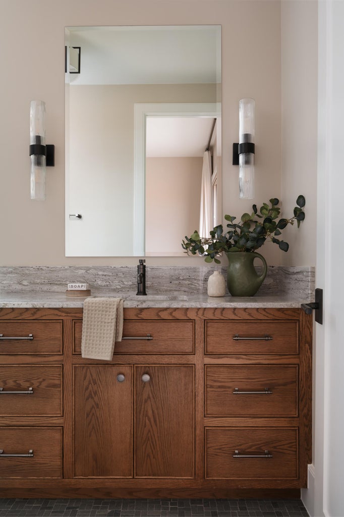 Custom wood vanity with a stone countertop, integrated sink, and matte black faucet