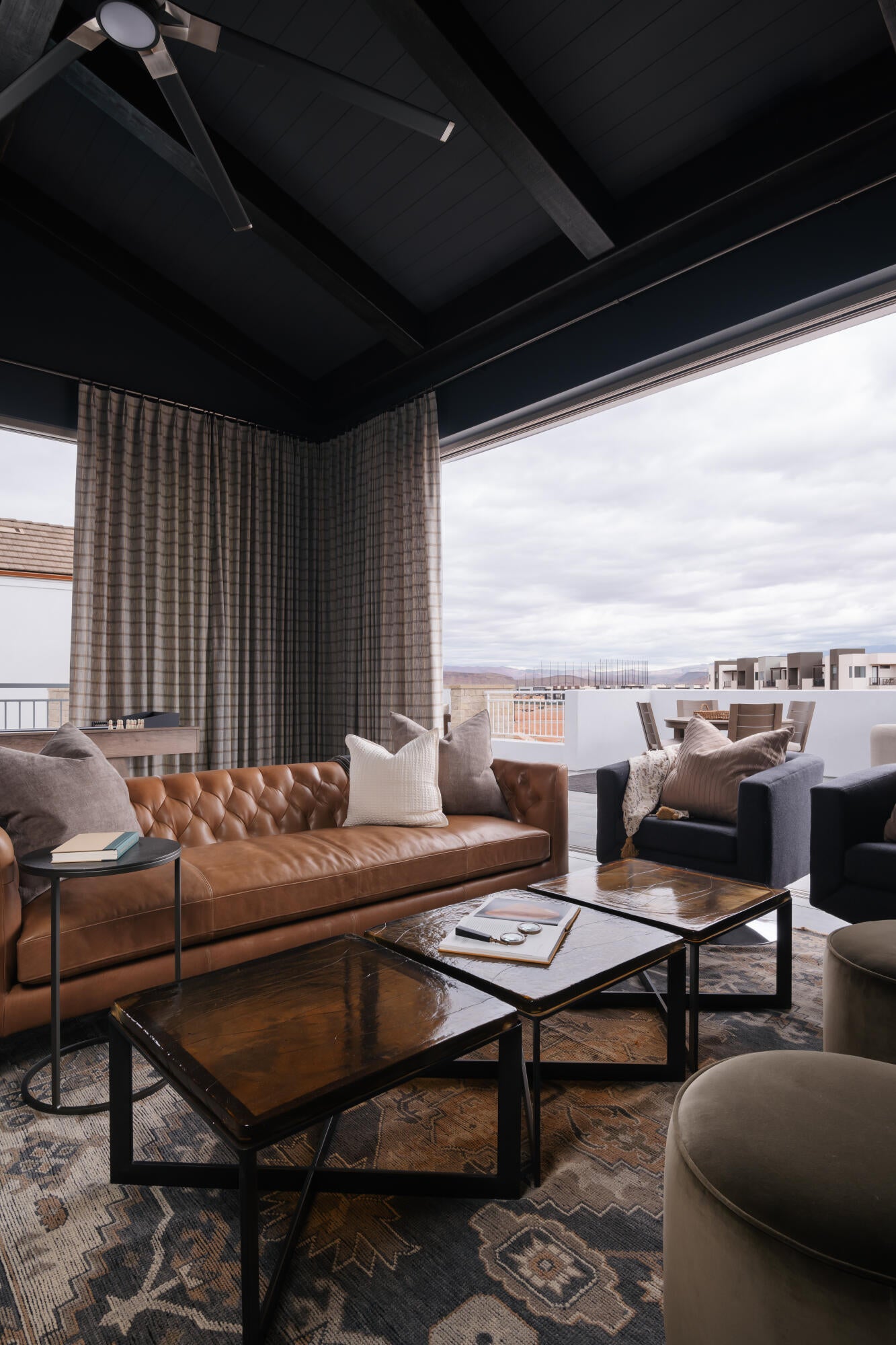 Vaulted ceiling with exposed beams, ceiling fan, and expansive sliding glass doors opening to an outdoor living space